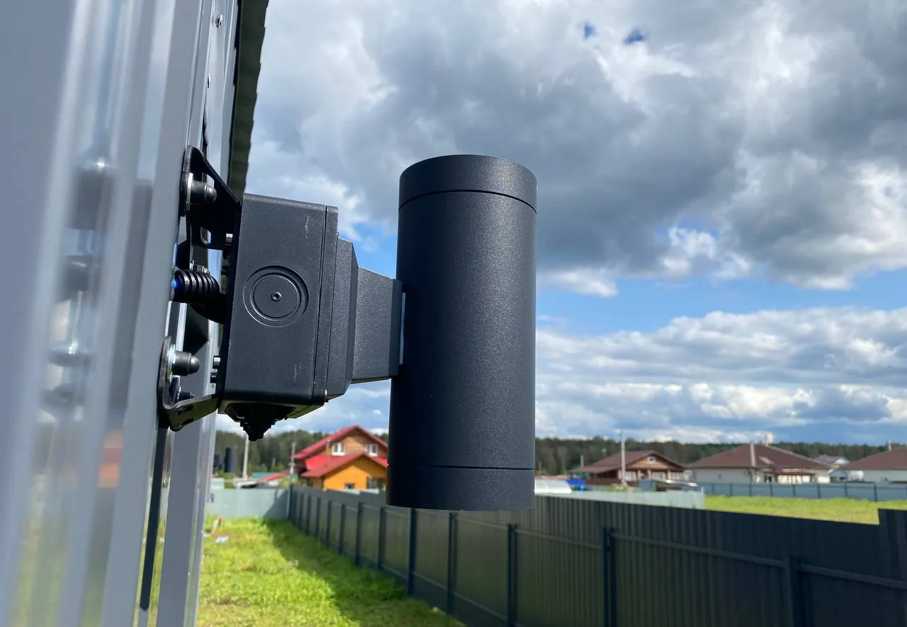 Тёмная монтажная коробка BOXFORCAM™ на регулируемом кронштейне на столбе ограждения, рядом светильник