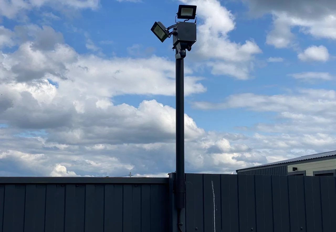 Мачта над забором: сверху коробка BOXFORCAM™, на ней два светодиодных прожектора, снизу купольная камера