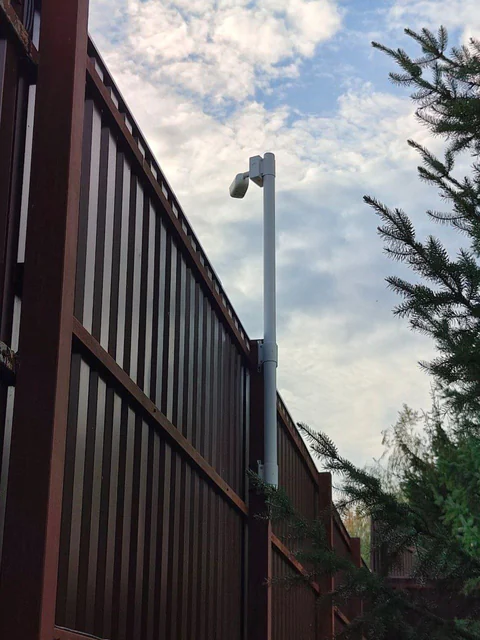 Трубостойка BOXFORCAM™ с камерой на секционном заборе, вид вдоль линии ограждения