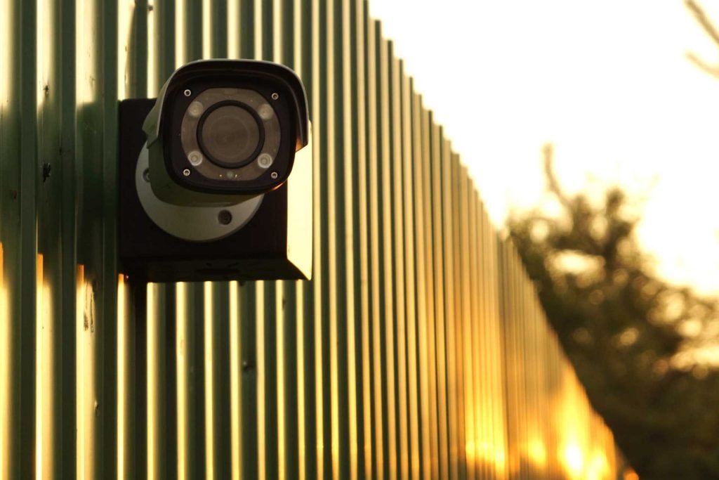 Камера на коробке BOXOFORCAM на зеленом металлическом заборе.